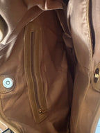 Close-up of a brown leather handbag or interior showing a zippered pocket, snap button closure, and interior pockets.