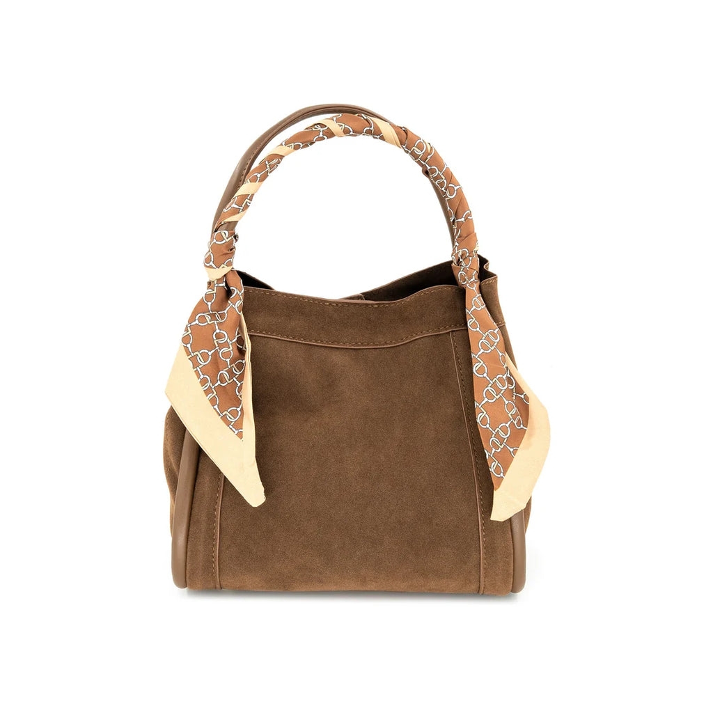A brown suede handbag with a tan and cream patterned scarf tied to its handles, shown against a plain white background.