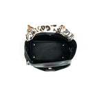 An open black handbag with a leopard-print fabric handle, photographed from a top-down view on a white background.